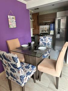 cocina con mesa, sillas y pared púrpura en Apartamento na Praia, en Ilhéus