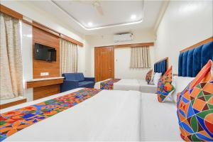 a hotel room with two beds and a tv at FabHotel HK Villa in Vadodara