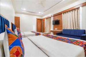 a hotel room with two beds and a tv at FabHotel HK Villa in Vadodara