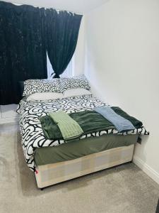 ein kleines Bett in einem Schlafzimmer mit schwarzen und weißen Bettbezügen in der Unterkunft City Dreams in Croydon