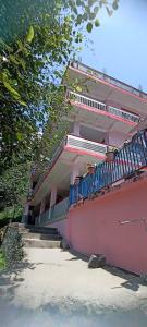 een roze gebouw met blauwe leuning aan de zijkant bij Tabassum guest house in Kasol