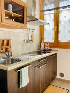 una cucina con armadi in legno, lavandino e finestra di Agriturismo La Selvaggia a Mandello del Lario