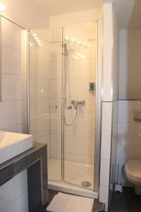 a bathroom with a shower with a sink and a toilet at Wiking Hotel in Henstedt-Ulzburg