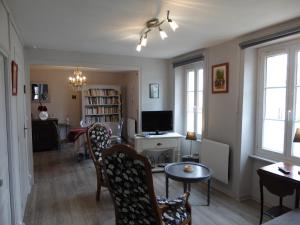 sala de estar con sillas, mesa y TV en Location Ker Bihan, en Saint-Lunaire