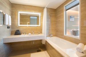 a bathroom with a sink and a tub and a mirror at Hotel Centralbay in Busan