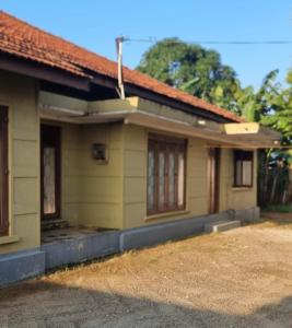 Holiday Bungalow for rent, Inuvil, Jaffna في Uduvil: منزل اصفر صغير بسقف احمر