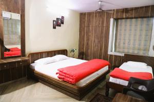 um quarto com uma cama com um cobertor vermelho e um espelho em Sikaria Homes em Ranchi