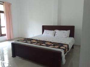 a bedroom with a large bed with a wooden headboard at Bosadi Homestay in Katunayake