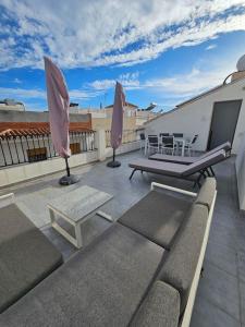 une terrasse sur le toit avec un canapé, une table et un parasol dans l'établissement San Pedro, à Nerja