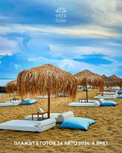 una playa con algunas sombrillas de paja y almohadas azules en Onyx Beach Residence - Free Parking & Beach Access en Sveti Vlas