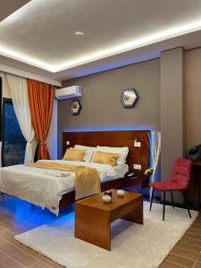 a bedroom with a large bed and a red chair at SKY KENAKO HOTEL in Kribi +49 photos