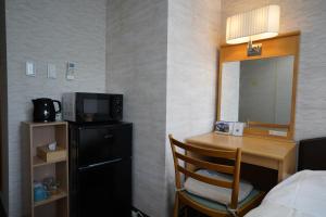 um quarto de hotel com uma secretária, uma cama e um espelho em The Hakuba Station Room em Hakuba