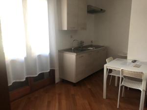 a kitchen with a sink and a table with chairs at Aurasol Alghero in Alghero