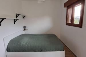 ein weißes Zimmer mit einem Bett und einem Fenster in der Unterkunft Maison maquis corse in Zicavo
