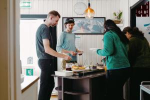 a group of people standing in a kitchen preparing food at Gjestehuset 102 in Longyearbyen