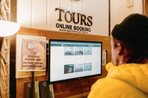 a man sitting in front of a computer monitor at Gjestehuset 102 in Longyearbyen