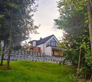 a house on a hill with a stone wall at Domki Dwa jelonki - balia z jacuzzi i sauna in Wisła