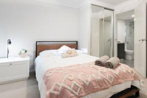 a white bedroom with a large bed and a bathroom at Executive CBD Perth House 4BR 3BA 2Pk SLEEP 8! in Perth
