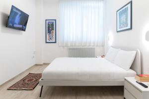 Un dormitorio blanco con una cama blanca y un televisor. en Cairoli Lifestyle, en Fano 28 fotos más