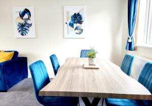 jadalnia z drewnianym stołem i niebieskimi krzesłami w obiekcie Terrance House, modern, spacious w mieście Carlisle