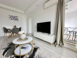 a white living room with a television and a table at Double Studio B601 StayInn by Cosmopolis in Ştefăneştii de Jos