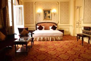 ein Schlafzimmer mit einem großen Bett und einem Tisch in der Unterkunft Windsor Palace Luxury Heritage Hotel Since 1906 by Paradise Inn Group in Alexandria