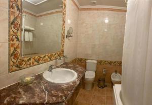 een badkamer met een wastafel, een toilet en een spiegel bij Windsor Palace Luxury Heritage Hotel Since 1906 by Paradise Inn Group in Alexandrië