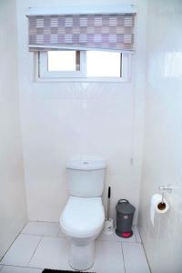 a white bathroom with a toilet and a window at Homely stay in the heart of Osu - Studio 2 in Accra