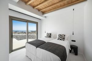 2 camas en un dormitorio con ventana grande en Deliades Hotel, en Ornos