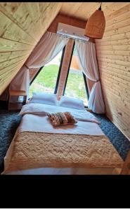 Bett in einem Zimmer mit einem großen Fenster in der Unterkunft CarpatinA Rustic House in Runcu