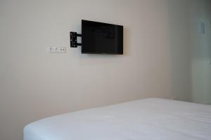 TV en una pared blanca sobre una cama en Estancia dos Olivos, en Quesa
