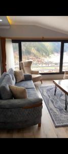 - un salon avec un canapé et une grande fenêtre dans l'établissement O'CHENA AKYUZ PAR in UZUNGÖL, à Çaykara