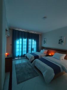 sypialnia z 2 łóżkami i oknem w obiekcie Ajami Hotel Armed Forces Apartments w Aleksandrii
