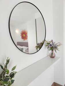 a round mirror on a white wall with flowers in a vase at King's Apartment in Baška