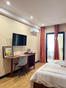a bedroom with a bed and a desk and a television at SKY KENAKO HOTEL in Kribi