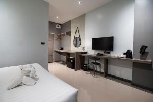 um quarto com uma cama e uma secretária com uma televisão em YSW Hotel Lopburi em Ban Khok Krathiam