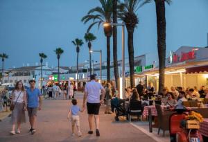 a group of people walking down a sidewalk in a city at Chalet Calan Bosch in Cala en Bosc