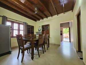 a dining room with a wooden table and chairs at Veda Villa Kundapura in Kundapur