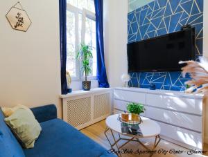 BaySide Apartments City Center في غدانسك: غرفة معيشة مع أريكة زرقاء وتلفزيون