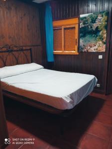 uma cama num quarto de madeira com uma janela em Complejo Godoy em Losar de la Vera
