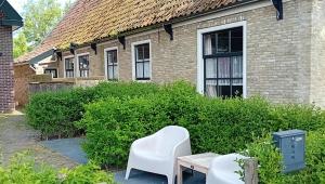 two white chairs and a table in front of a building at Appartement de Hoge Stoep in Hollum