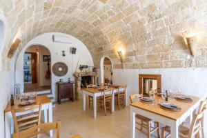 een eetkamer met tafels en een bakstenen muur bij Trappito Stracca Agriturismo Masseria didattica in Alezio