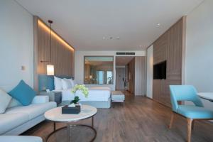 una camera d'albergo con un letto e un divano di Căn hộ cao cấp tại ALaCarte Ha Long Bay Hotel Residence a Ha Long