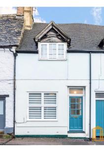 une maison blanche avec une porte et des fenêtres bleues dans l'établissement West End one-bedroom flat Witney, Oxfordshire, à Witney