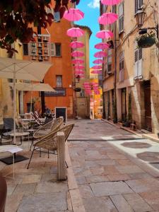 un groupe de parapluies roses suspendus au-dessus d'une rue dans l'établissement Joli 2 pièces centre historique de Grasse, WIFI, à Grasse