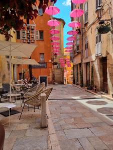 a group of pink umbrellas hanging over a street at Joli 2 pièces centre historique de Grasse, CLIM ET WIFI in Grasse