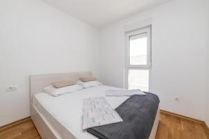 a white bedroom with a large bed with a window at Luxury Apartment Maglica in Makarska