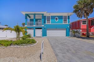 a blue house with a garage and palm trees at Inn-2-Blue - 155 Jefferson St home in Fort Myers Beach