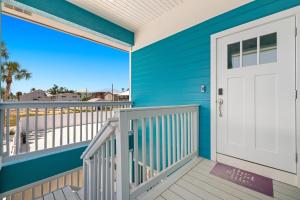 une maison bleue avec une porte blanche sur un balcon dans l'établissement Inn-2-Blue - 155 Jefferson St home, à Fort Myers Beach