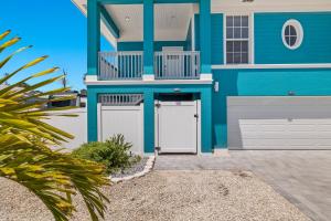a blue house with two white garage doors at Inn-2-Blue - 155 Jefferson St home in Fort Myers Beach